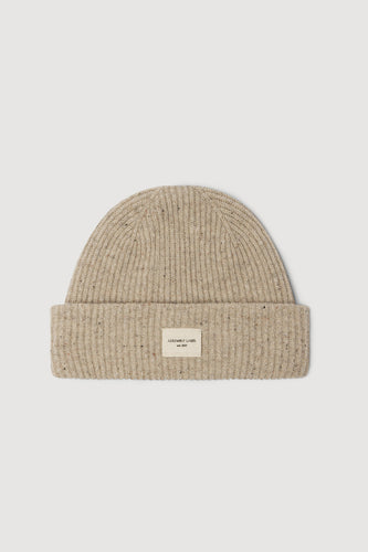 Beige knit beanie with a small label on a light gray background