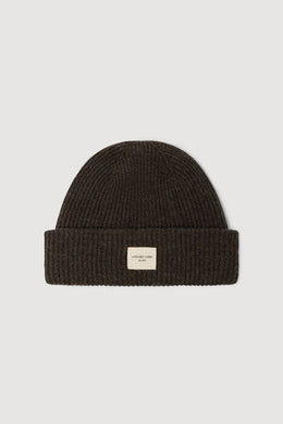 Dark brown knit beanie with a small label on a light gray background