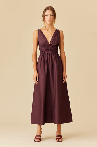 Woman wearing a burgundy dress against a beige background