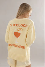 Woman wearing a yellow sweater with '5 O'Clock Somewhere' text and wine glass graphic.