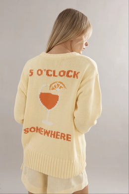 Woman wearing a yellow sweater with '5 O'Clock Somewhere' text and wine glass graphic.